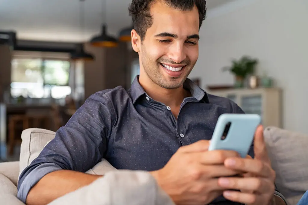 Man at home holding his smartphone using the Bitwarden password manager to create a passphrase