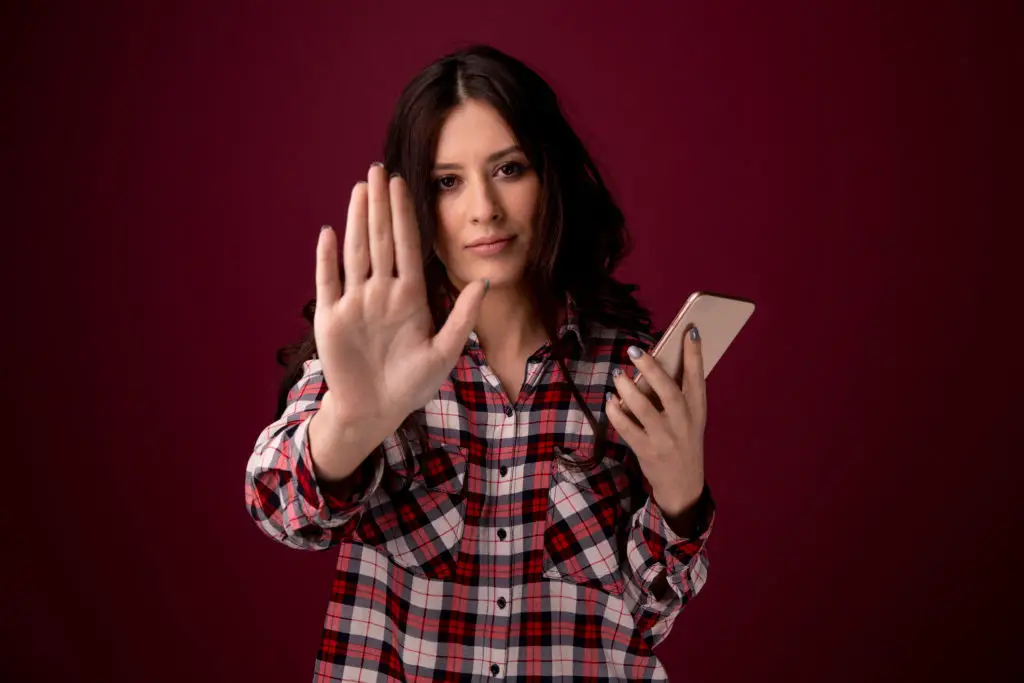 Woman holding up a hand to stop stealing social media photos for fake profile pictures