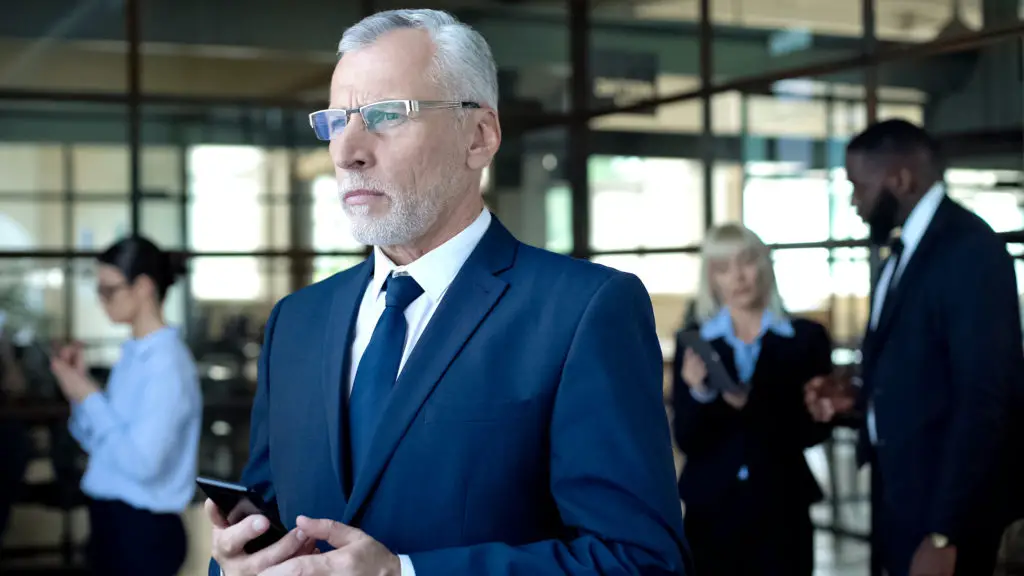 Concerned executive holding his smartphoine after receiving a whaling type phishing attempt
