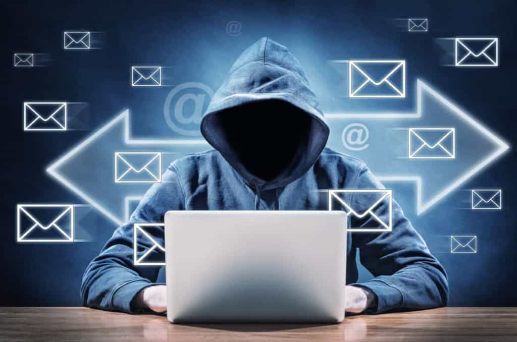 Hacker on a laptop with conceptual images of emails behind them. How do you know if your email has been hacked.