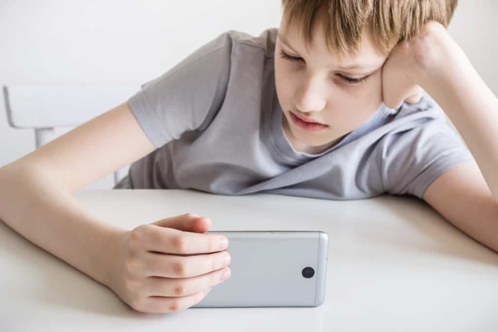 Teenage boy watch video on smartphone wondering if he should turn mobile data on or off