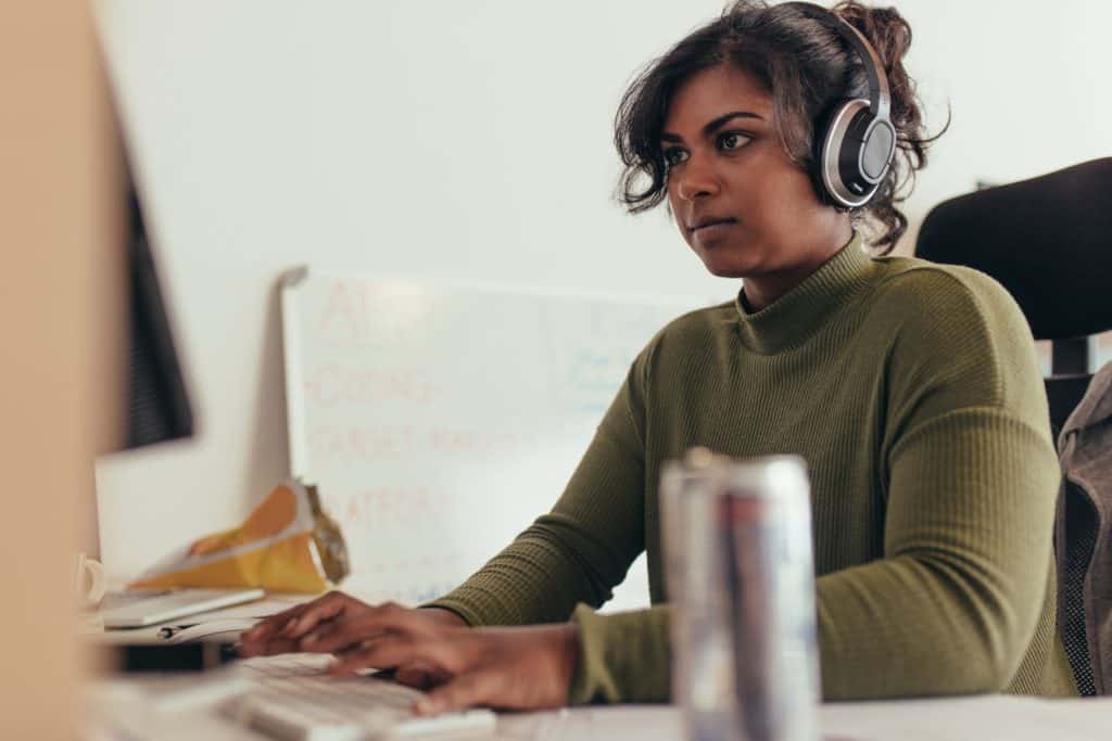 Confident woman wearing headphones at computer working hard at her cyber security job