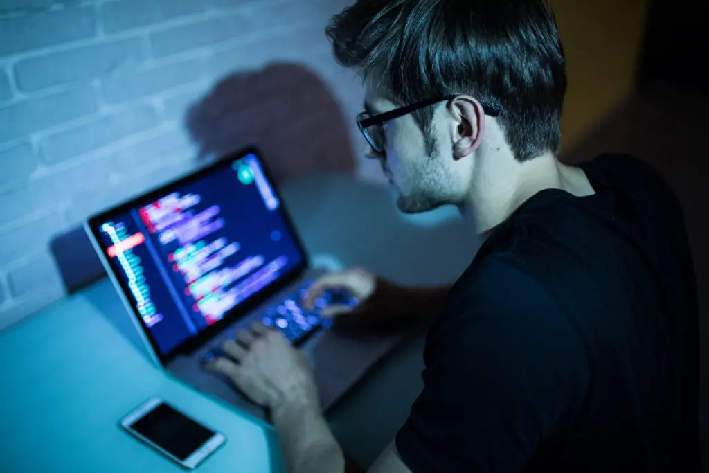 Man with laptop on desk while programming open source secure code