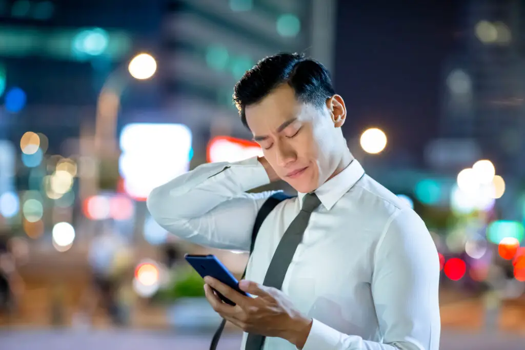 Businessman holding a smartphone worried because he accidentally clicked on spam link
