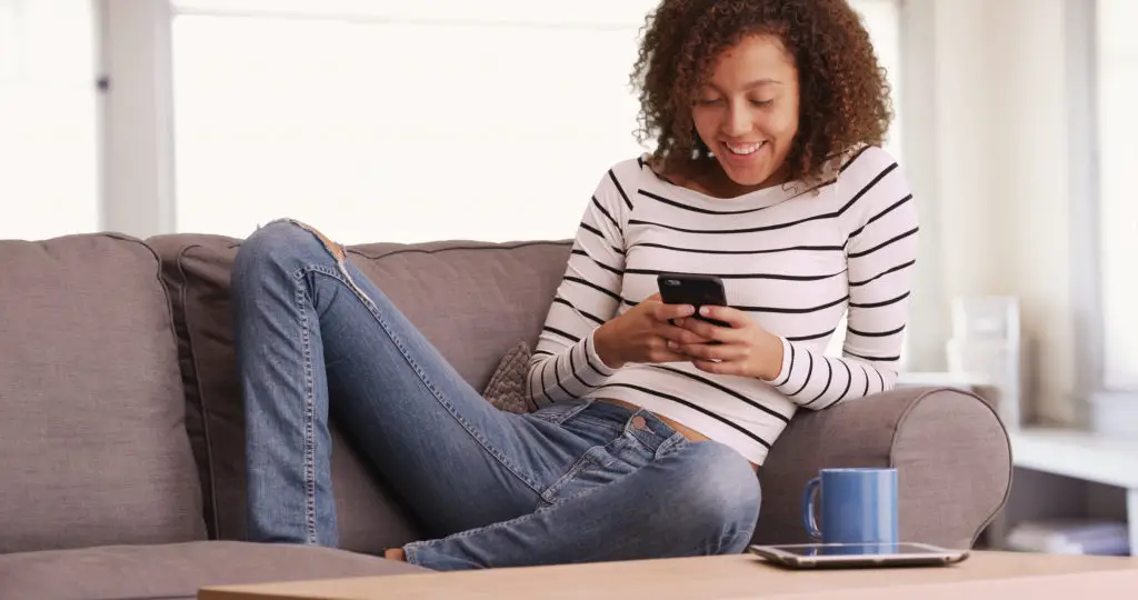 Woman on couch texting because she knows you can use a phone without a sim card
