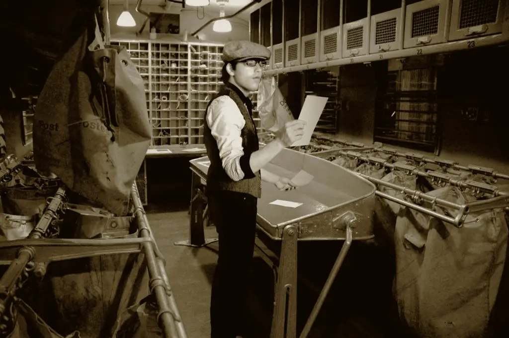 Sepia photo of clerk in a train car mail room which is how fake email address forwarding works