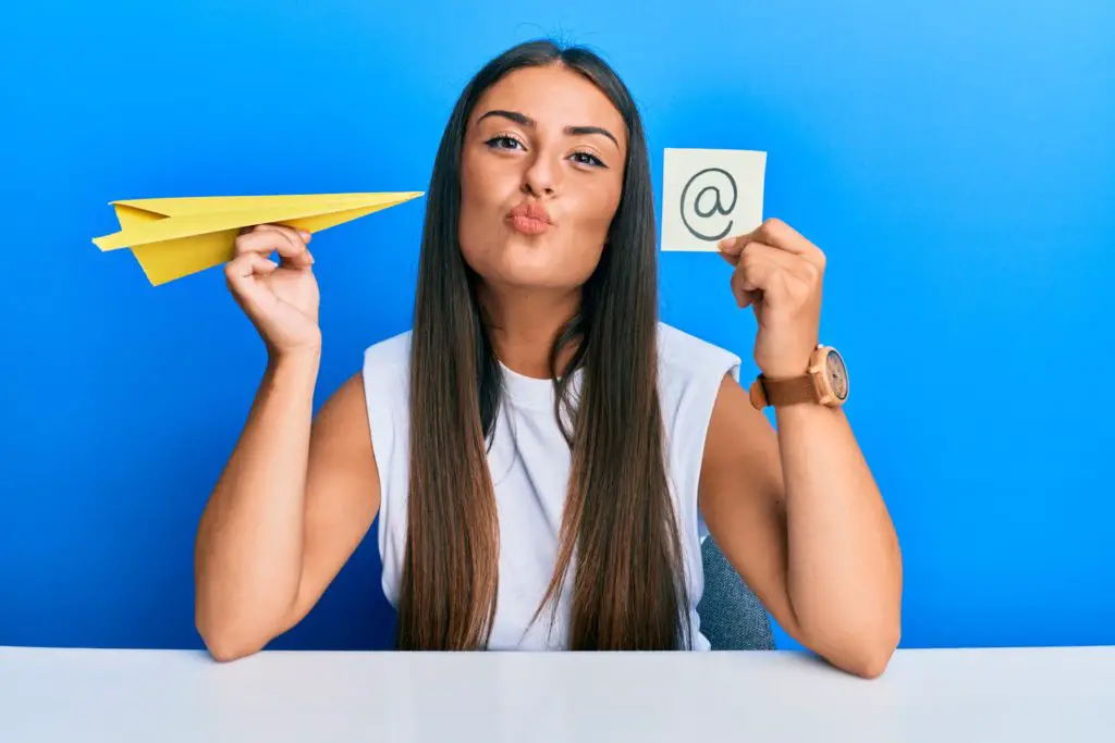 Woman holding paper plane and at symbol with a confident expression, knowing how to use a fake email address