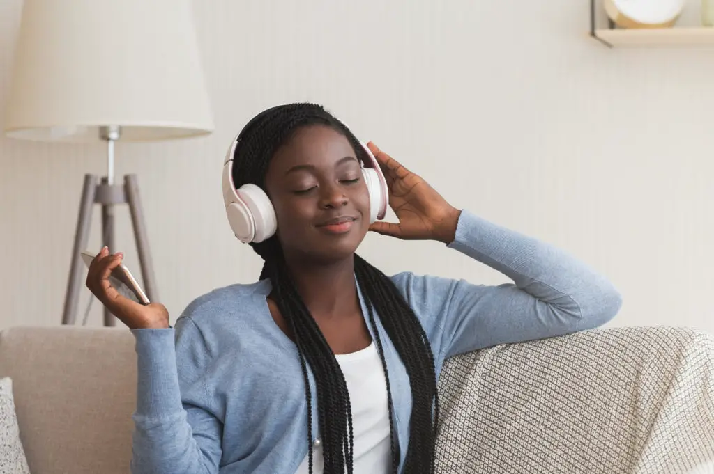 Woman on sofa listening to music on headphones that paired with nfc & bluetooth