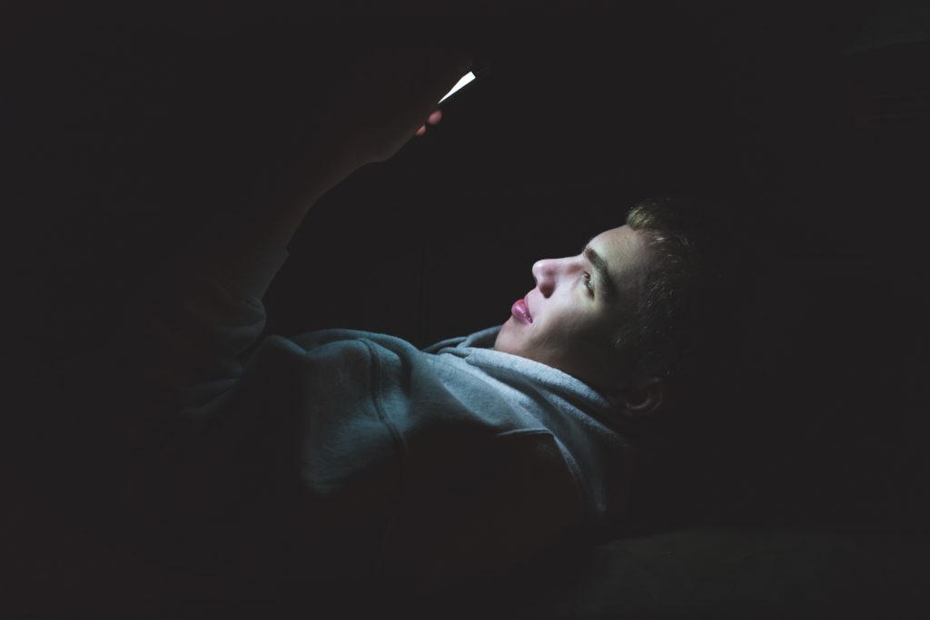 Teenager in the dark holding a smartphone watching youtube advert-free