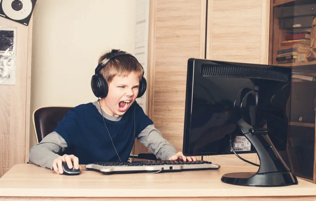 Boy in headphones screaming at computer.
