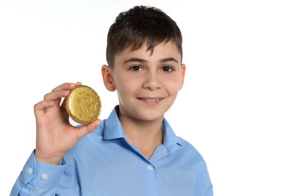 Cheerful boy holding an overly large bitcoin.
