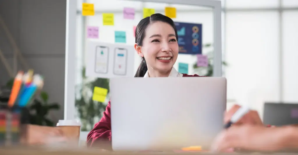Smiling business woman behind laptop looking to make a social media app