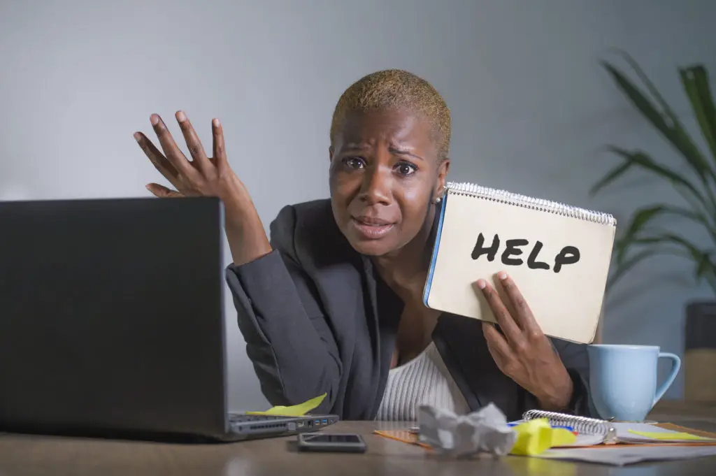 Worried woman with laptop holding a help note