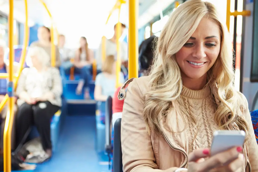 Woman on bus checking text message on her phone.