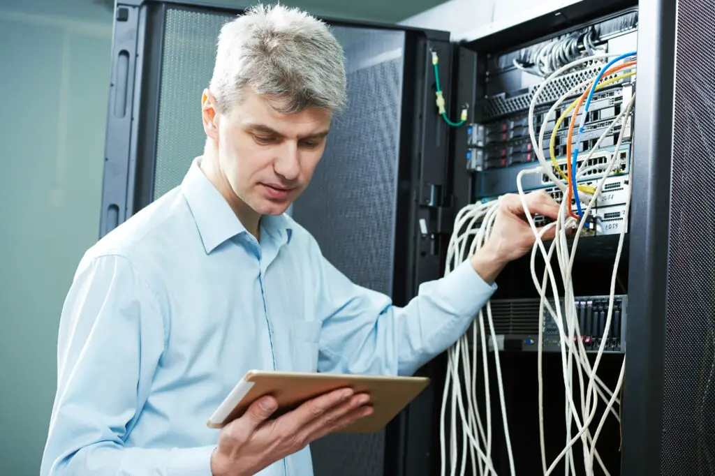 Male database administrator doing a systems check in the server room.