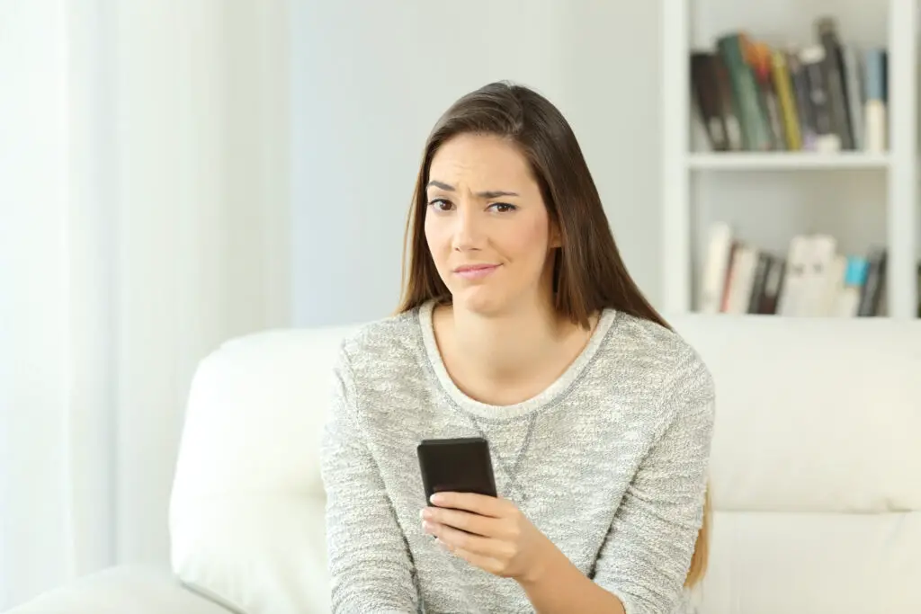 Woman holding a smartphone with a suspicious look wondering if a free number for whatsapp is a good idea