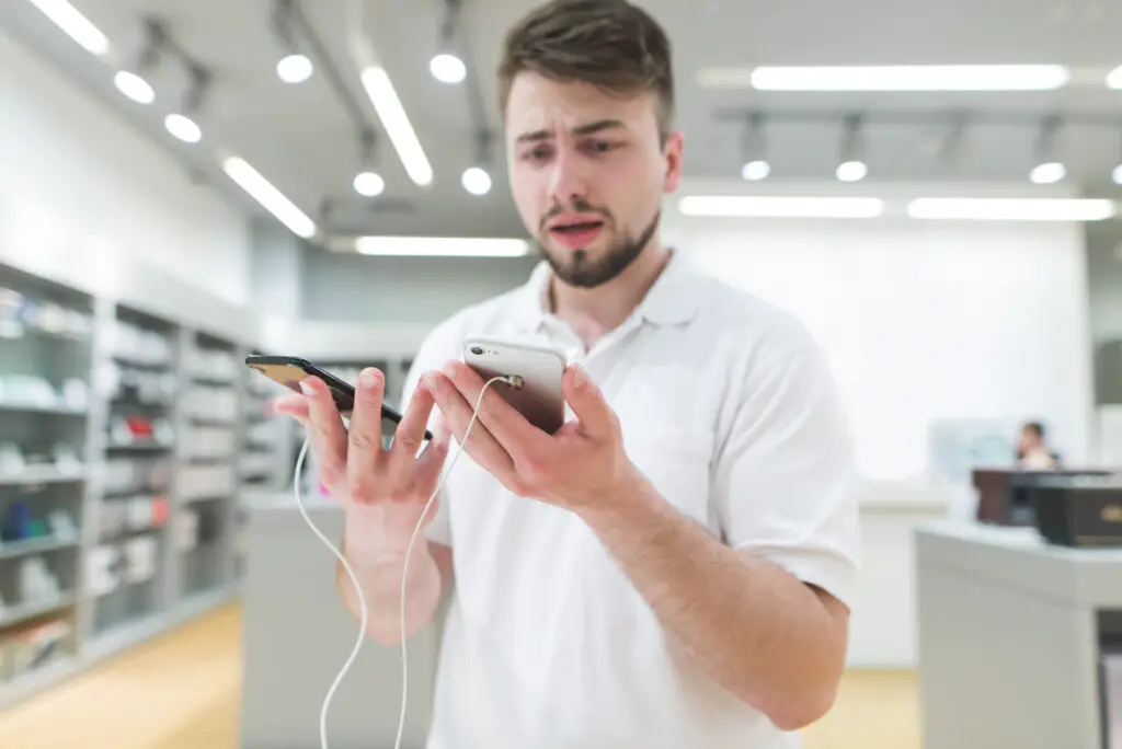 Man in store holding two smartphones wondering how to transfer an esim to a new phone