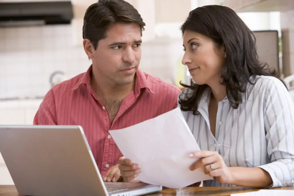 Parents with laptop looking at phone bill, worried about who's been making calls