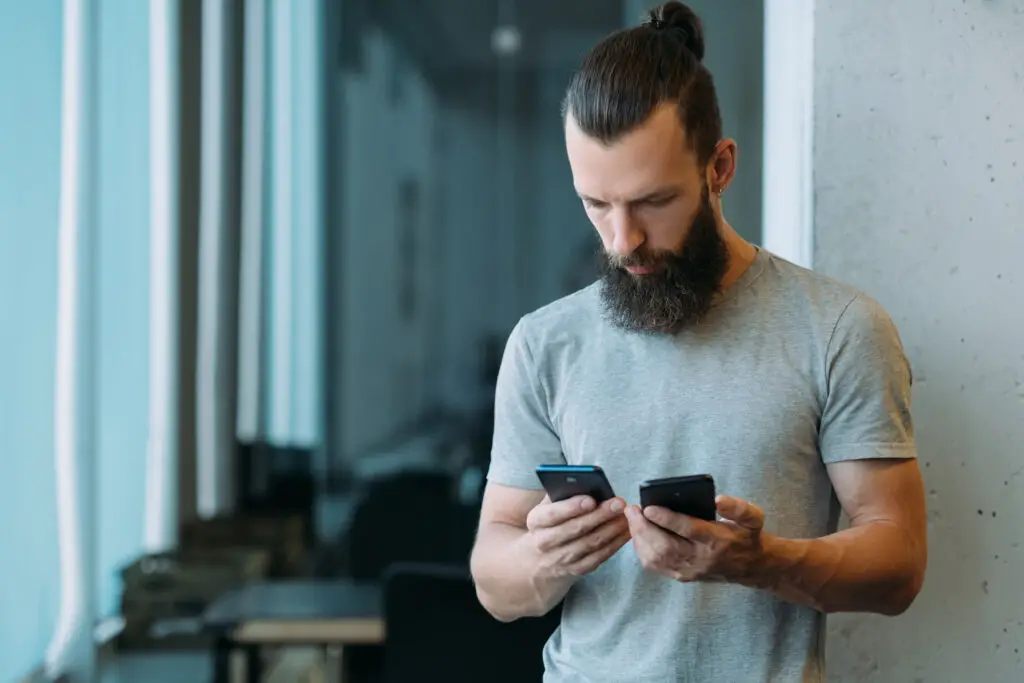 Man holding two smartphones using one to keep some calls off the phone bill