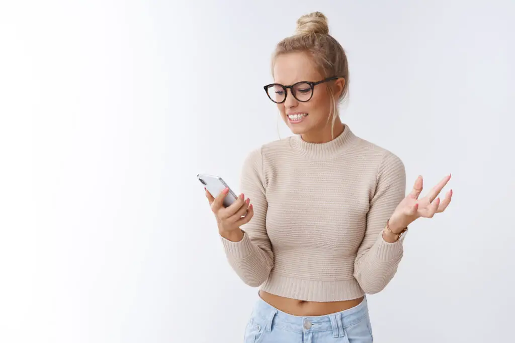 Frustrated woman holding smartphone wondering how can someone hack your email without a password.