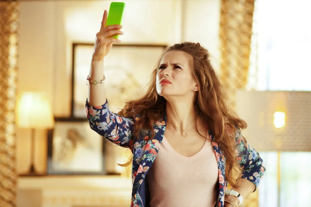 Confused woman holding smartphone in the air wondering do mobile phones have ip addresses